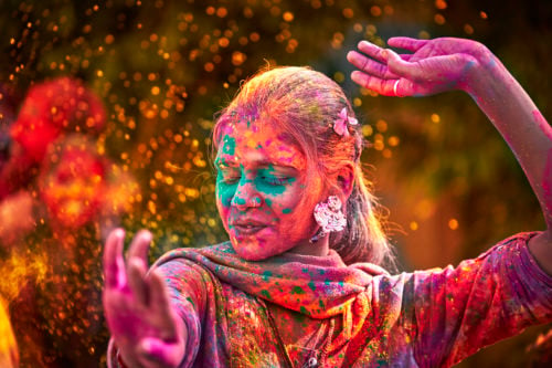 Portrait Of Young Indian Woman With Colored Face Dancing During Holi