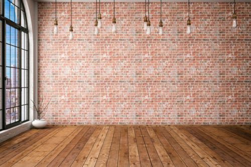 Room with wooden floor and brick wall, and bare bulbs hanging from the ceiling.