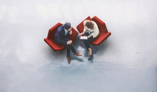 man-and-woman-sitting-in-office-chairs-discussing-professional-workspace