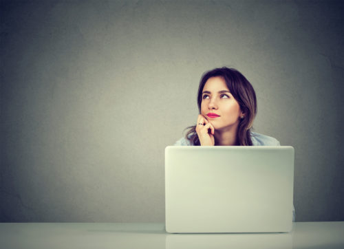 woman-resting-chin-on-hand-while-working-on-laptop